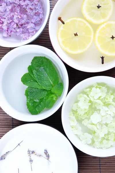 Aromterapi behandling skålar med blommor och parfymerat vatten på bambu matta bakgrund — Stockfoto