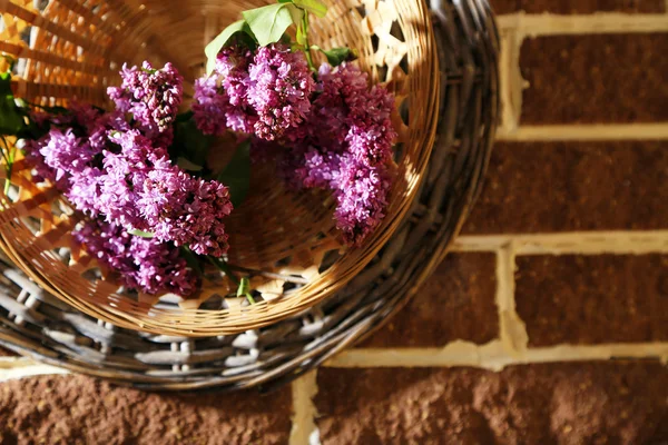 Hermosas flores de color lila en canasta de mimbre sobre fondo de piedras de color — Foto de Stock