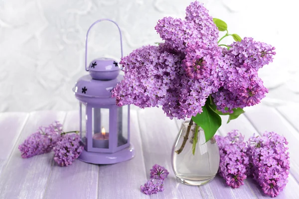 Beautiful lilac flowers in vase on table on light background — Stock Photo, Image