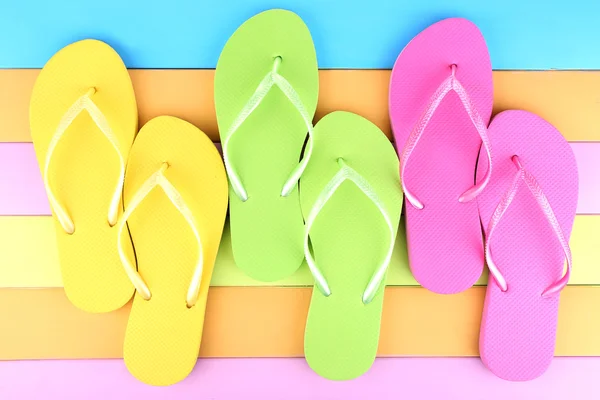 Bright flip-flops on color wooden background — Stock Photo, Image