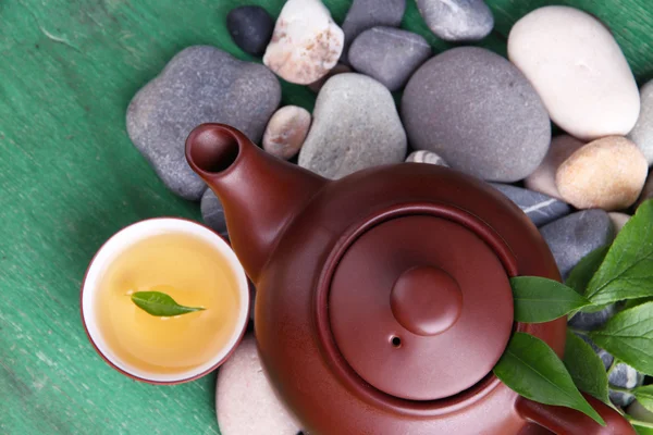 Teapot with dry flowers and herbs ingredients for tea, on stones and color wooden background — Stock Photo, Image