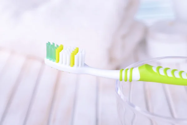 Zahnbürste im Glas auf Tisch auf hellem Hintergrund — Stockfoto