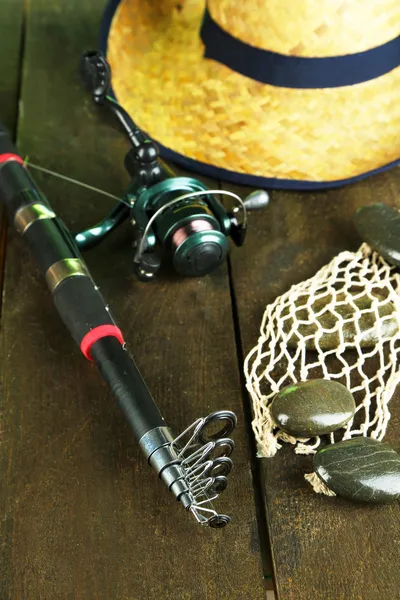 Canna da pesca, stivali di gomma e cappello sul tavolo di legno primo piano — Foto Stock