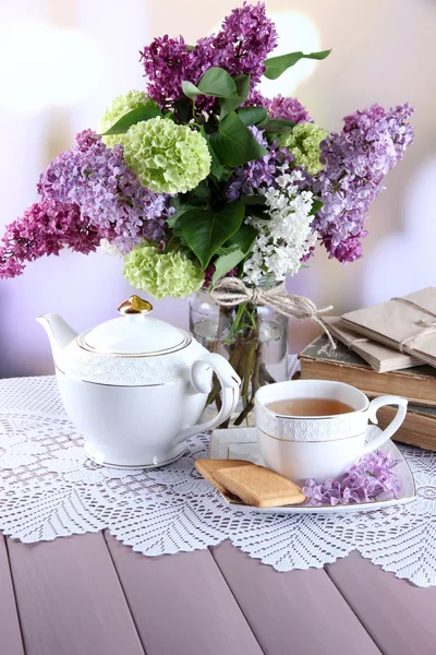 Composizione con teiera, tazza e bellissimi fiori primaverili in vaso, su tavolo di legno, su sfondo luminoso — Foto Stock