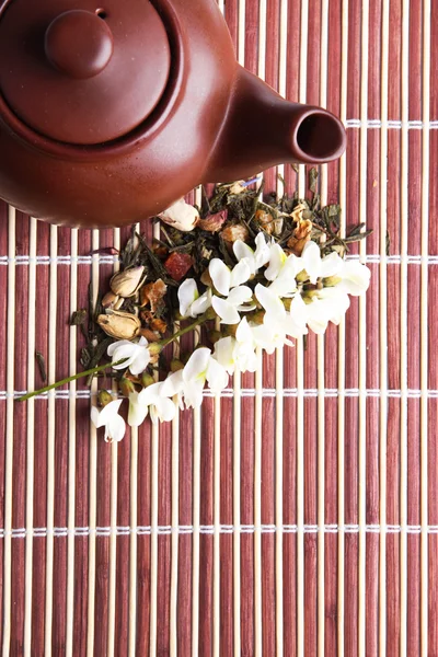 Infuso di tisana floreale naturale con ingredienti di fiori secchi, su sfondo tappetino di bambù — Foto Stock