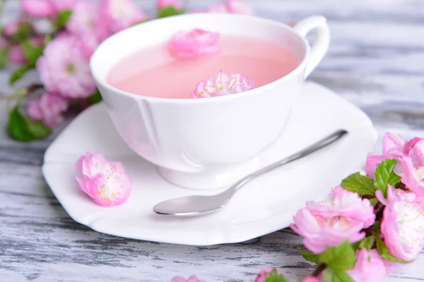 Beautiful fruit blossom with cup of tea on table close-up — Stock Photo, Image