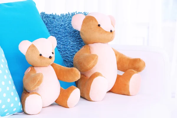 Две медвежьи игрушки с подушками на диване — стоковое фото