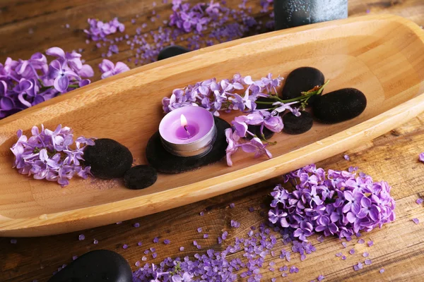 Composition with wooden bowl with water and lilac flowers, on wooden background — Stock Photo, Image