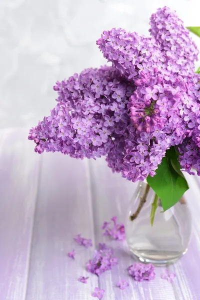 Beautiful lilac flowers in vase on table on light background — Stock Photo, Image