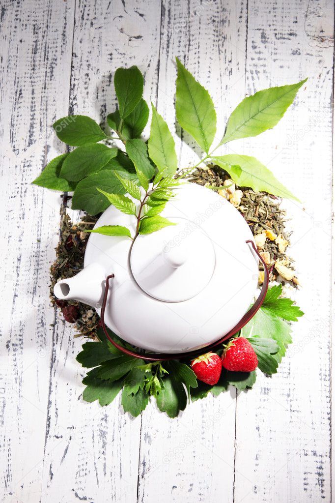Herbal natural tea in teapot with dry flowers and herbs ingredients, on color wooden background