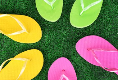 yeşil çim zemin üzerine parlak parmak arası terlik