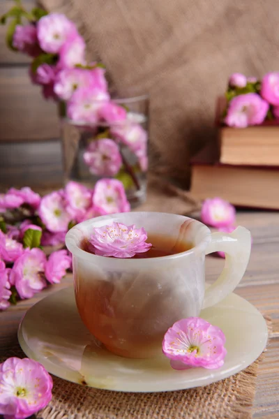 Mooie fruit blossom met kopje thee op tafel op grijze achtergrond — Stockfoto