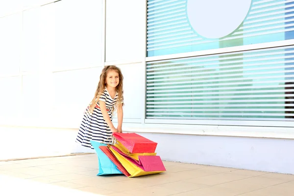 Glad liten flicka med shop väskor, utomhus — Stockfoto