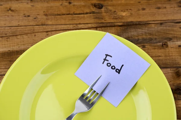 Note paper with message  attached to fork, on plate, on color wooden background — Stock Photo, Image