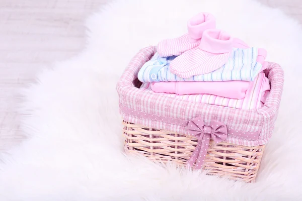 Babykläder i korg på golvet i rum — Stockfoto