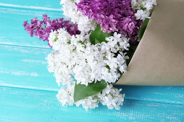 Beautiful bouquet of lilac flowers on color wooden background — Stock Photo, Image