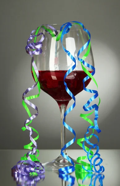 Glass of red wine and streamer after party on gray background
