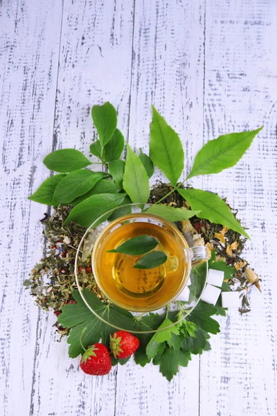 Composizione con fiori secchi foglie fresche e frutta ingredienti per tazza di tè e vetro, su sfondo di legno a colori — Foto Stock