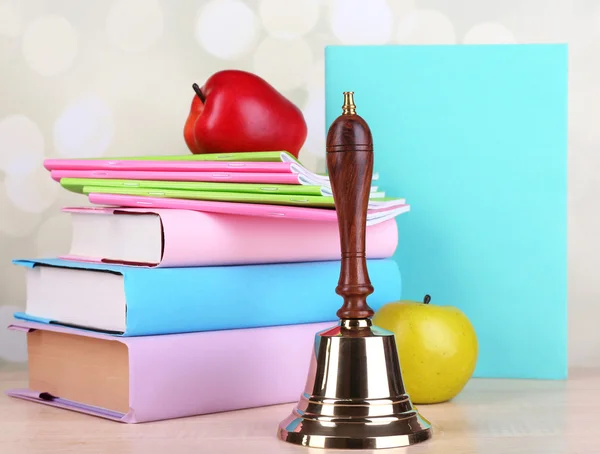 Gold school bell with school supplies on table on bright background — Stock Photo, Image