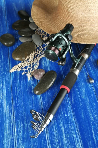 Fishing rod, gumboots and hat on wooden table close-up — Stock Photo, Image