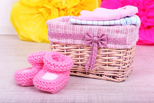 Baby clothes in basket on floor in room — Stock Photo, Image