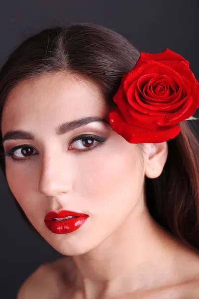 Κορίτσι με τα κόκκινα χείλη και τριαντάφυλλο σε σκούρο φόντο — Φωτογραφία Αρχείου