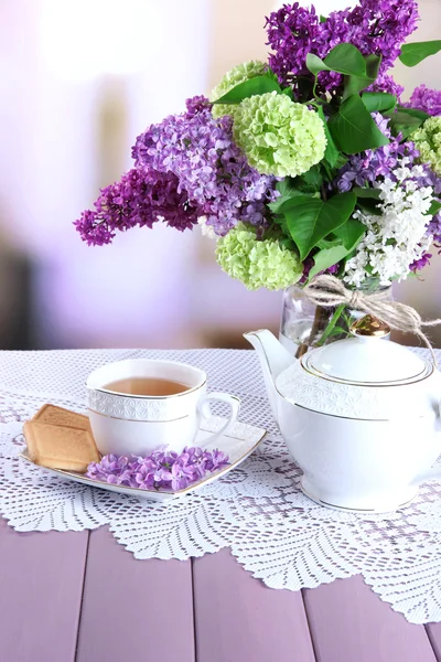 组成与茶壶、 杯子和美丽的春天鲜花插在花瓶里，木制的桌子，在明亮的背景上 — 图库照片