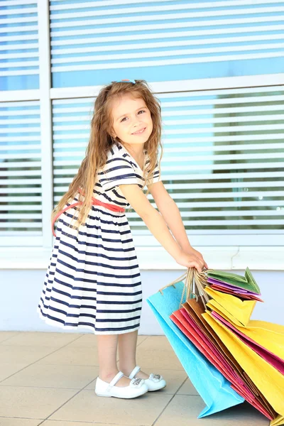 Bonne petite fille avec des sacs de magasin, en plein air — Photo