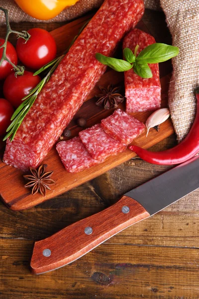 Salsicha de salame saboroso e especiarias em fundo de madeira — Fotografia de Stock