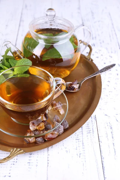 Composition of fresh mint tea in glass cup and teapot on tray, on wooden background — Stock Photo, Image