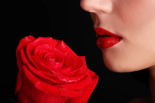 Mädchen mit roten Lippen und Rose auf dunklem Hintergrund — Stockfoto