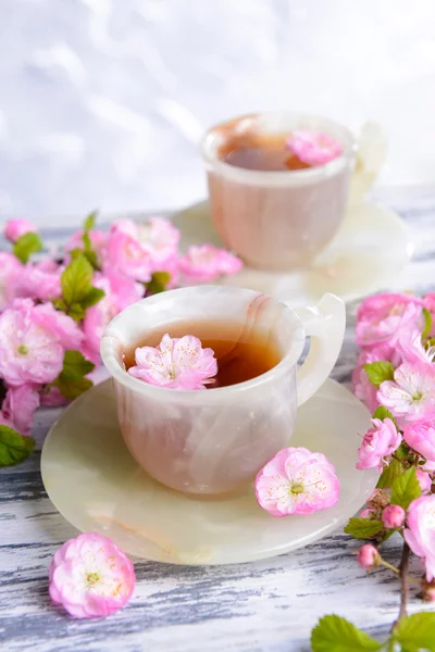 Mooie fruit blossom met kopje thee op tafel op grijze achtergrond — Stockfoto