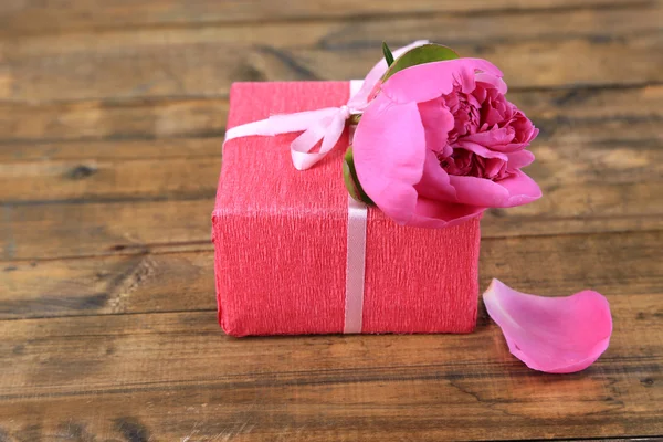 Regalo rosa con fiocco e fiore sul tavolo in legno primo piano — Foto Stock