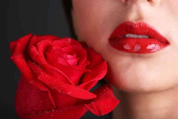 Mädchen mit roten Lippen und Rose auf dunklem Hintergrund — Stockfoto