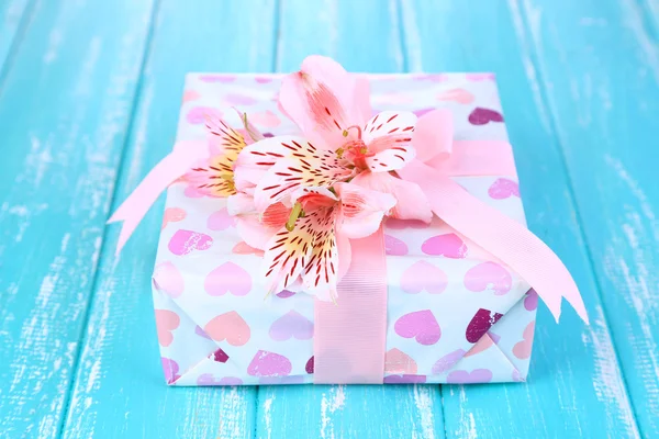 Regalo rosa con lazo y flor en mesa de madera de primer plano —  Fotos de Stock