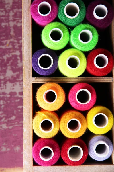 Linha de costura multicolor em caixa de madeira, em fundo de madeira, close-up — Fotografia de Stock