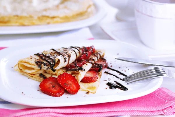 Deliciosos panqueques con fresas y chocolate en plato en la mesa — Foto de Stock