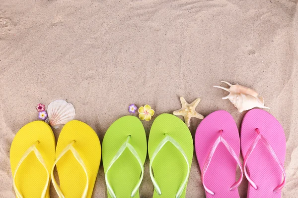 Bright flip-flops on sand, close up — Stock Photo, Image