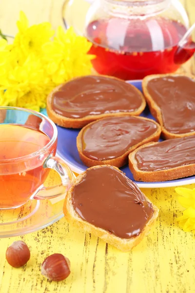 Pão com avelã de chocolate doce espalhado na placa na mesa — Fotografia de Stock