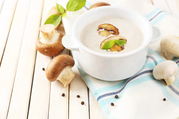 Mushroom soup in white pot, on napkin, on wooden background — Stock Photo, Image