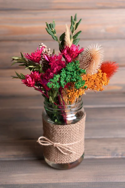 Гарний букет з яскравих квітів у банці на столі на сірому фоні — стокове фото