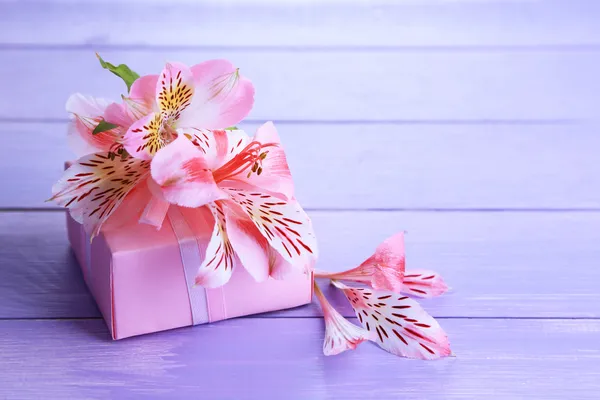 Regalo rosa con lazo y flor en mesa de madera de primer plano —  Fotos de Stock
