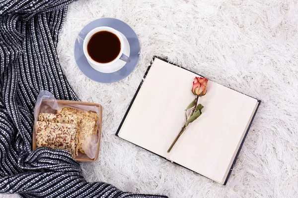 Composición con cuadros calientes, libro, taza de bebida caliente sobre fondo de alfombra de color —  Fotos de Stock