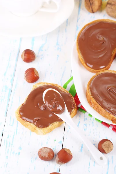 Pan con avellana de chocolate dulce extendido en el plato en la mesa — Foto de Stock