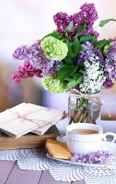 Composition avec théière, tasse et belles fleurs printanières dans un vase, sur une table en bois, sur un fond lumineux — Photo