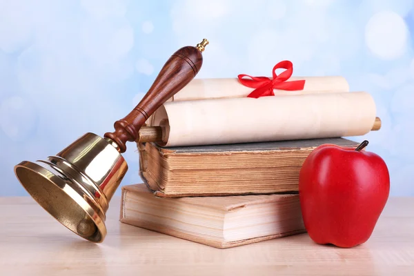 Gold school bell with school supplies on table on bright background — Stock Photo, Image