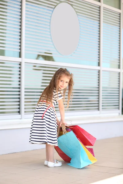 Glad liten flicka med shop väskor, utomhus — Stockfoto