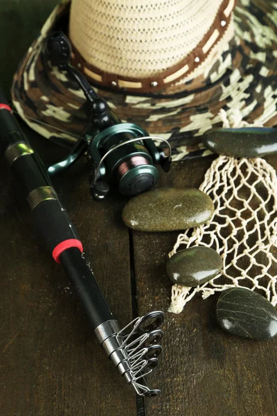 Canna da pesca, stivali di gomma e cappello sul tavolo di legno primo piano — Foto Stock