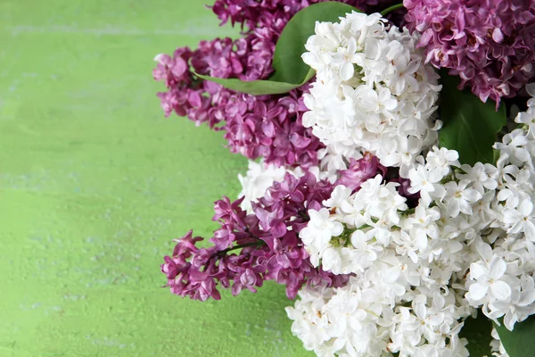 Beautiful bouquet of lilac flowers on color wooden background — Stock Photo, Image