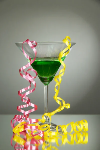 Стакан коктейля и стример после вечеринки на сером фоне Стоковое Изображение